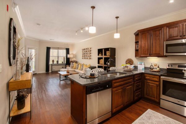 Highlands Lodge apartment kitchen with wood style floor and cabinets, stone counters, and stainless steel appliances.