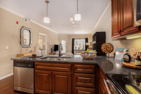 Highlands Lodge apartment kitchen with wood style floor and cabinets, stone counters, and stainless steel appliances.