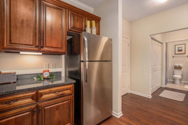 Highlands Lodge apartment kitchen with wood style floor and cabinets, stone counters, and stainless steel appliances.