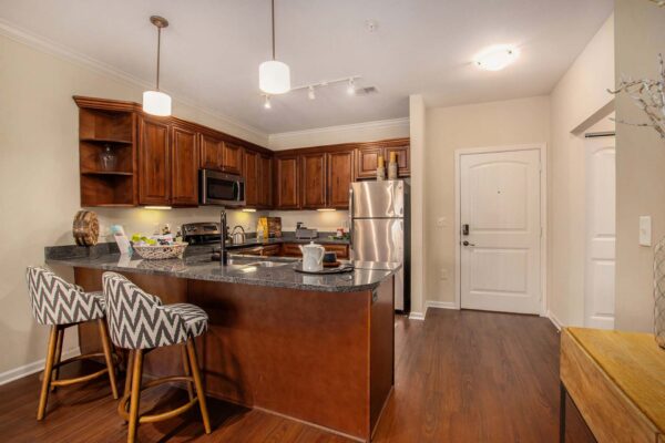 Highlands Lodge apartment kitchen with wood style floor and cabinets, stone counters, and stainless steel appliances.