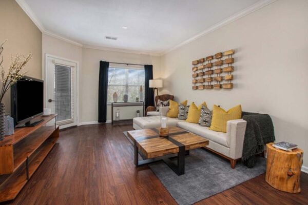 Highlands Lodge apartment living room with wood style floor, plush couch, and wood console with TV.