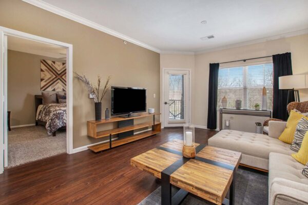 Highlands Lodge apartment living room with wood style floor, plush couch, and wood console with TV.