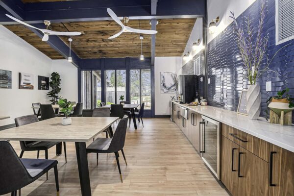 Kenilworth apartments community kitchen with wood style floor and cabinets, stainless steel appliances, and large tables.