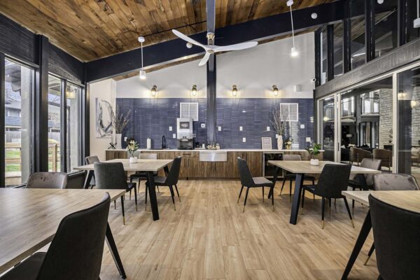 Kenilworth apartments community kitchen with wood style floor, large tables, vaulted ceilings, and large windows.