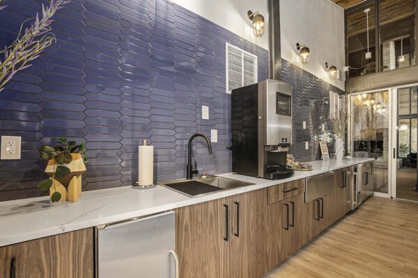 Kenilworth apartments community kitchen with wood style floor and cabinets, stainless steel appliances, and tiled backsplash.