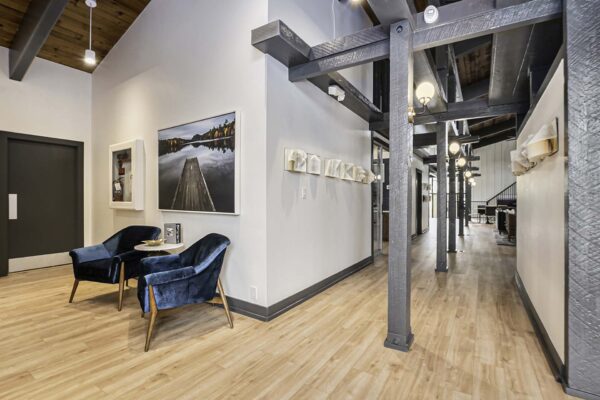 Kenilworth apartments clubhouse with wood style flooring, exposed wood beams, and plush seating.