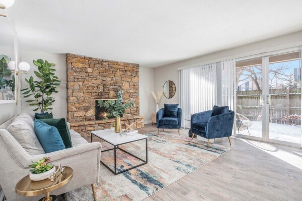 Kenilworth apartment living room with wood style floor, stone fireplace, plush seating, and balcony door.