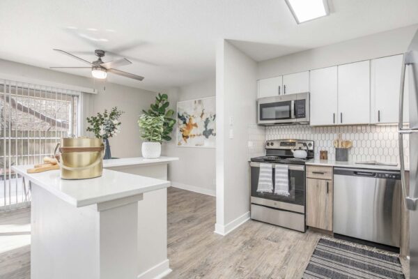 Kenilworth apartment kitchen with wood style floor, white cabinets and counters, and stainless steel appliances.