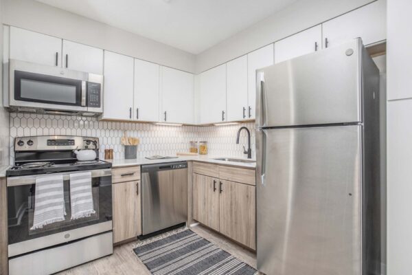 Kenilworth apartment kitchen with wood style floor, white cabinets and counters, and stainless steel appliances.