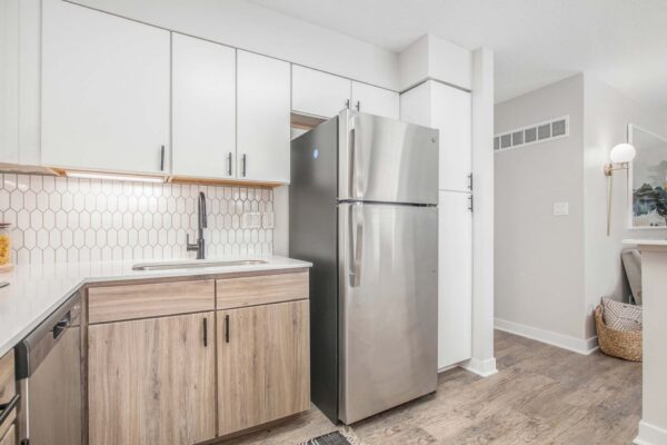 Kenilworth apartment kitchen with wood style floor, white cabinets and counters, and stainless steel appliances.