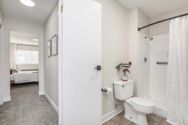 Kenilworth apartment bathroom with wood style floor and tiled shower.