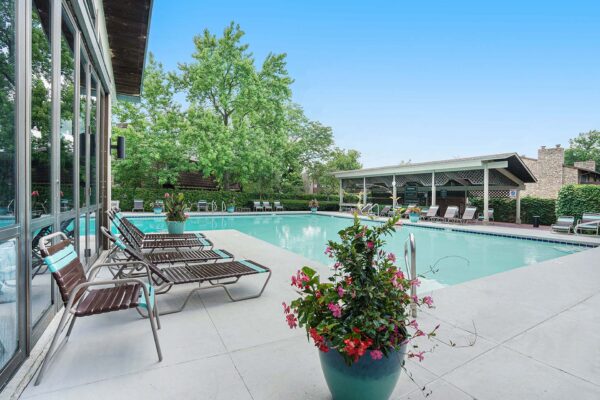 Kenilworth apartments pool area with lounge chairs and large potted plants.