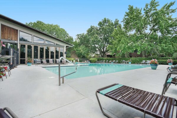 Kenilworth apartments pool area with lounge chairs and large potted plants.