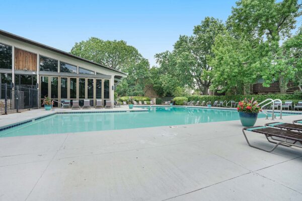 Kenilworth apartments pool area with lounge chairs and large potted plants.
