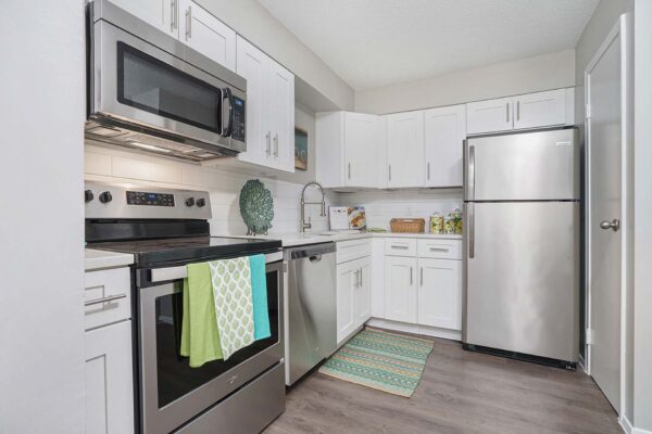 Kenilworth apartment kitchen with wood style floor, white cabinets and counters, and stainless steel appliances.