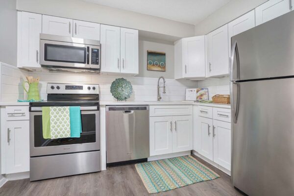 Kenilworth apartment kitchen with wood style floor, white cabinets and counters, and stainless steel appliances.