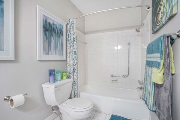 Kenilworth apartment bathroom with tile floor, framed artwork, and tiled shower tub.