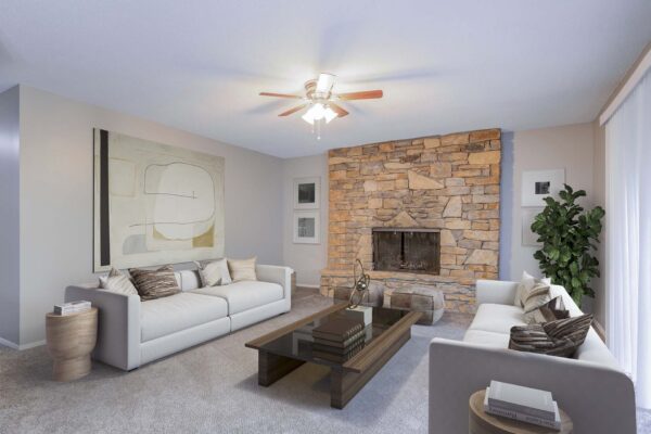 Kenilworth apartment living room with carpet, plush seating, stone fireplace, and ceiling fan.