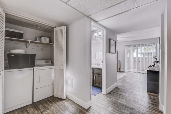 Latitude apartment hallway with bathroom door and laundry closet with washer and dryer.