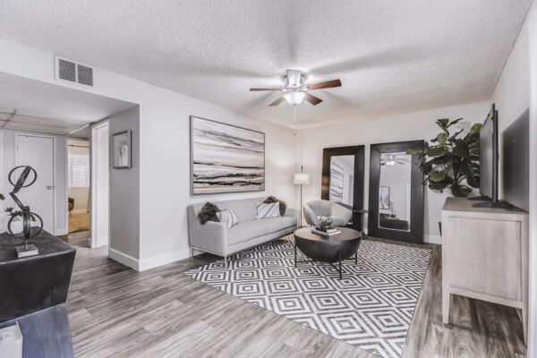Latitude apartment living room with wood style floor, plush seating, large mirrors, and framed artwork.