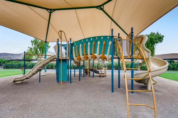Latitude apartments playground with large awning and metal play equipment.