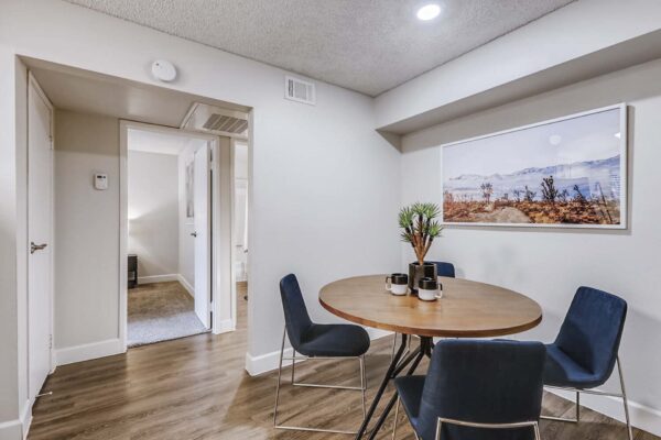 Latitude apartment dining room with wood style floor, round dining table with chairs and framed photo.