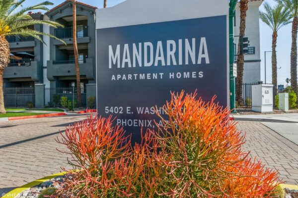 Mandarina apartments entrance with colorful flowers and monument sign.