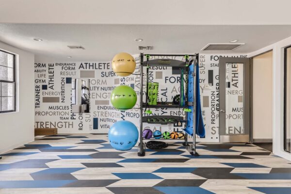Mandarina apartments fitness center with calisthenics equipment and motivational mural.