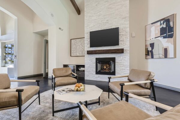 Mandarina apartments lobby with leather arm chairs, fireplace, wall mounted TV, and artwork.