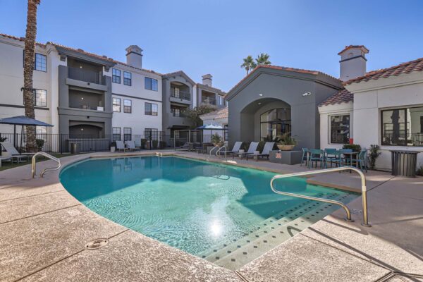 Mandarina apartments pool area with lounge chairs, dining tables, and clubhouse.