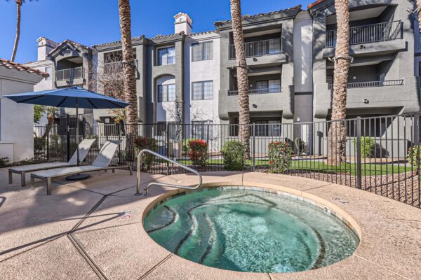 Mandarina apartments pool area with hot tub, lounge chairs, and tall palm trees.