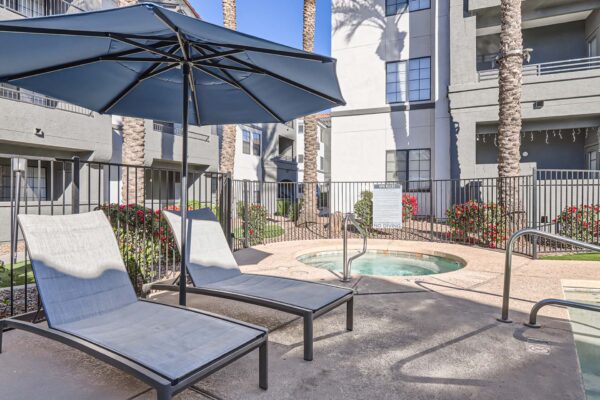 Mandarina apartments pool area with hot tub, lounge chairs, and umbrellas.