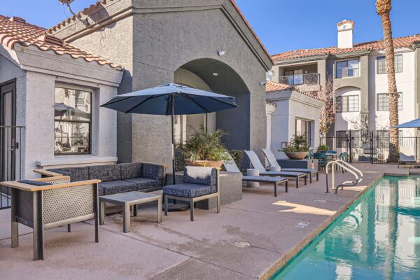 Mandarina apartments pool area with lounge chairs, umbrellas, and clubhouse.