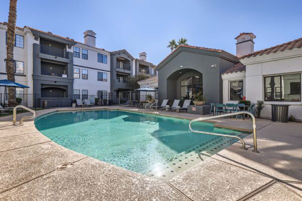 Mandarina apartments pool area with lounge chairs and clubhouse.
