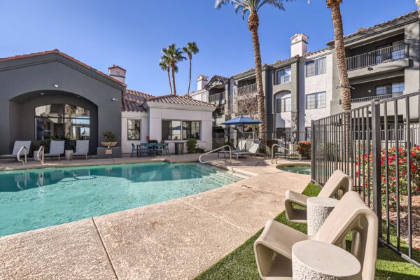 Mandarina apartments pool area with lounge chairs, umbrellas, and tall palm trees.