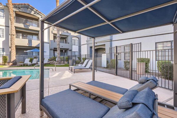 Mandarina apartments pool area with covered lounge chairs and metal fence.