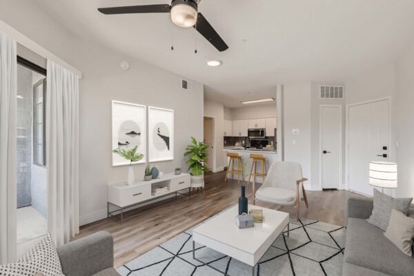 Mandarina apartment living room with plush seating, modern decor, framed art, and ceiling fan.