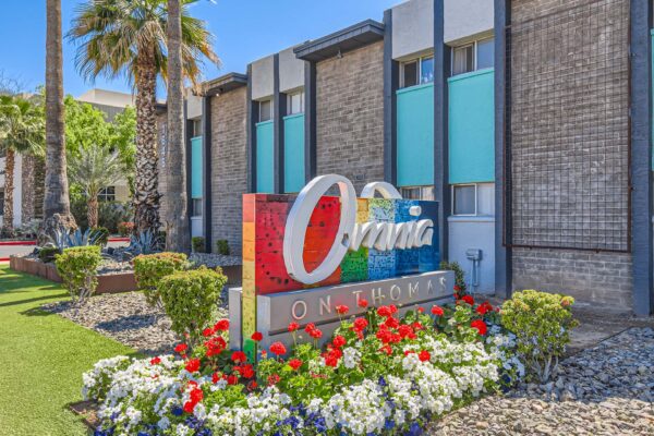 Omnia on Thomas apartments entrance with colorful monument sign and lush landscaping.
