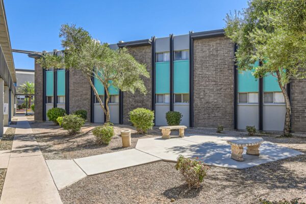 Omnia on Thomas apartments courtyard with paved walkways, stone benches, and tall trees.