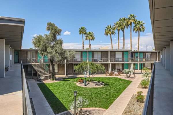 Omnia on Thomas apartments courtyard with paved walkways, lush lawn, and tall trees.
