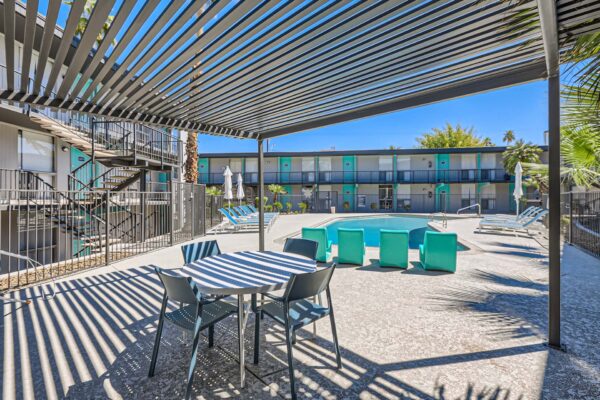 Omnia on Thomas apartments pool area with lounge chairs, dining table, and pergola.