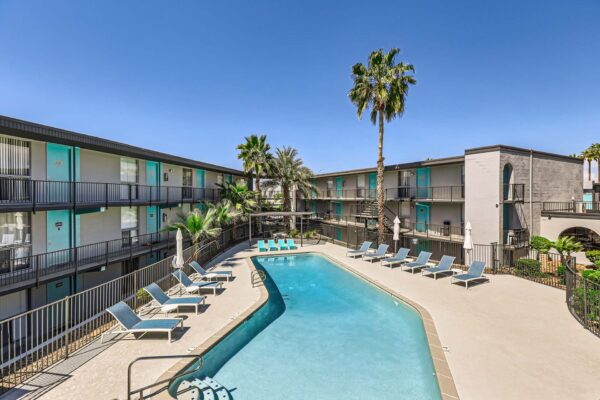 Omnia on Thomas apartments pool area with lounge chairs and tall palm trees.
