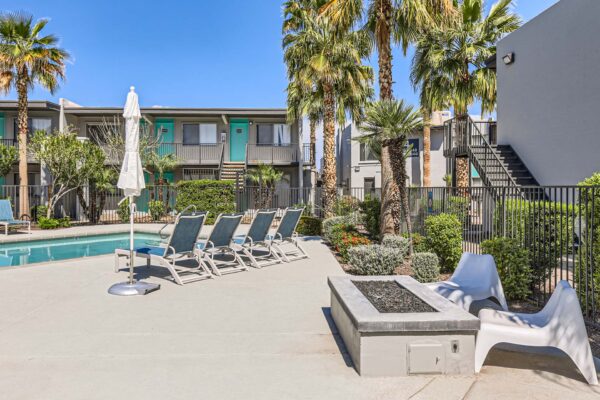 Omnia on Thomas apartments pool area with lounge chairs, umbrellas, and fire pit.