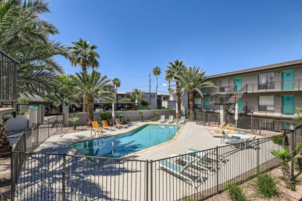 Omnia on Thomas apartments pool area with lounge chairs and metal fence.