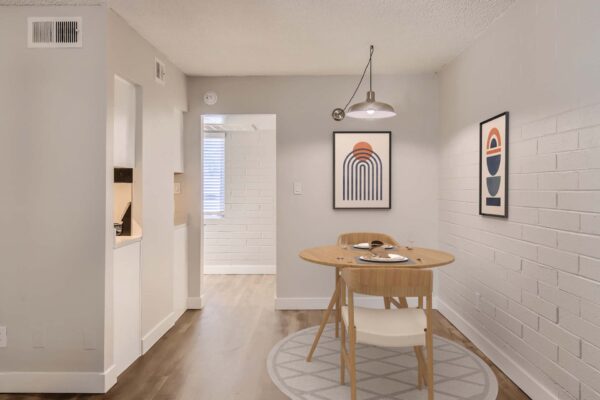 Omnia on Thomas apartment dining area with wood table, stools, and framed artwork.