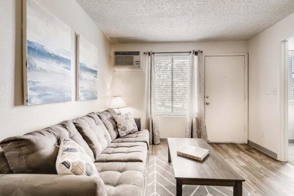 Overlook at Sunset Point apartment living room with plush couch, wall art, and coffee table with book.