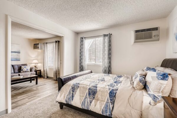 Overlook at Sunset Point apartment bedroom with carpet, plush bedding, and large window.