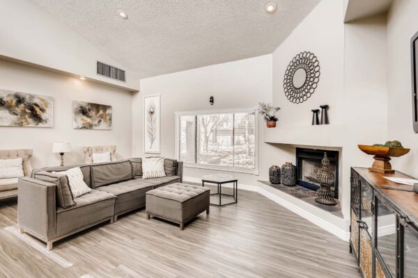 Overlook at Sunset Point apartments clubroom with plush seating, fireplace, large window, and vaulted ceilings.
