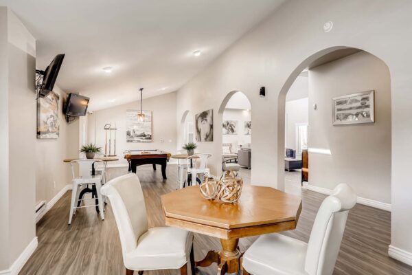 Overlook at Sunset Point apartments clubhouse with dining tables, TVs, and pool table.