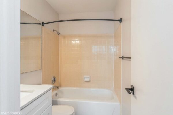 Overlook at Sunset Point apartment bathroom with white cabinets and counters and peach-color tiled shower tub.